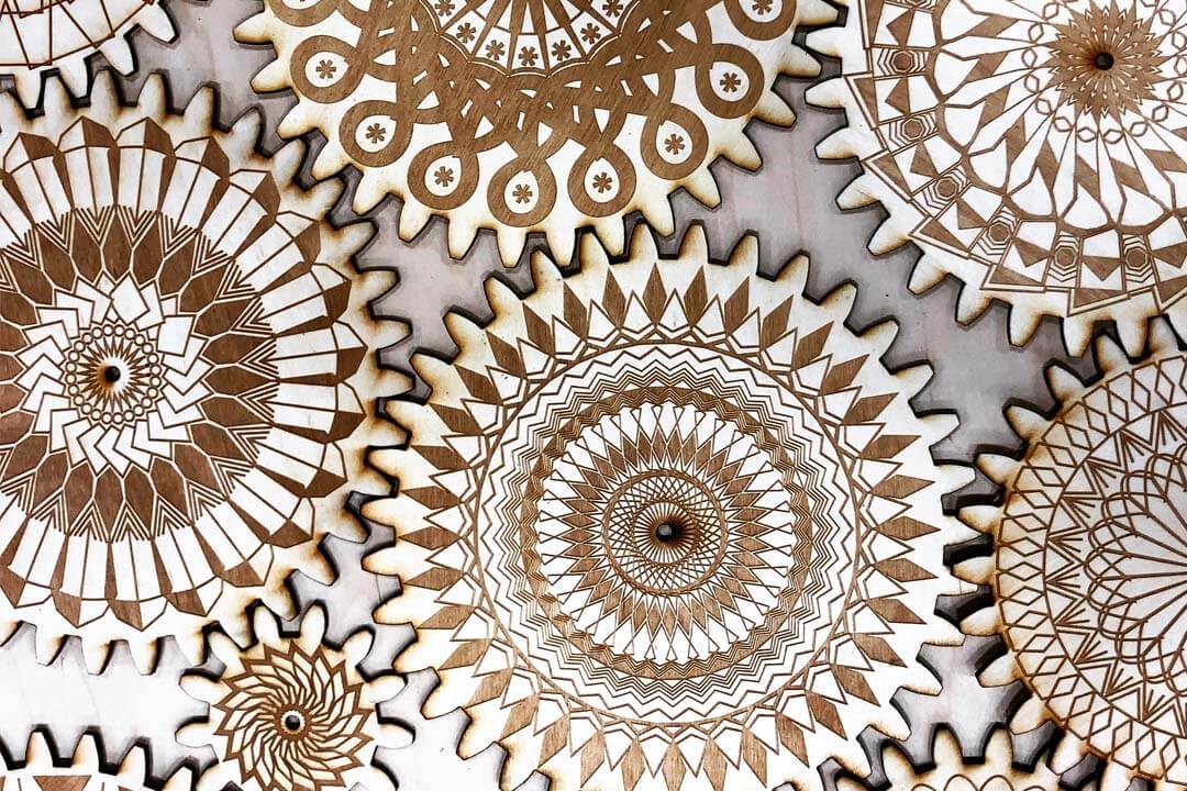 Photo taken of light balsa wood that has been laser-engraved to look like gears with pattern designs